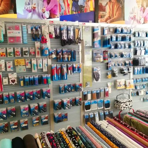 Kurzwaren Bunt sortierte Nähmaterialien wie Garne, Knöpfe und Bänder in einem Geschäft angeordnet.