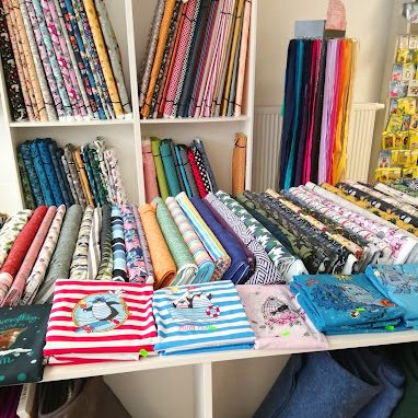 Stoffe Eine Sammlung von bunten Stoffen in verschiedenen Mustern und Farben auf Regalen.